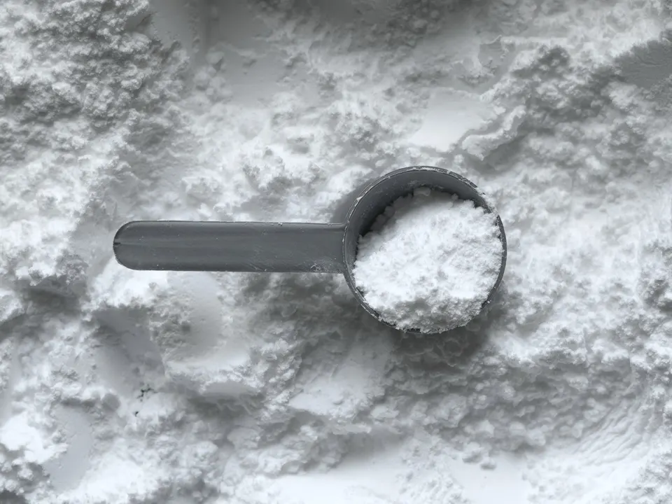 Fine white powder in a scoop, shown for illustration